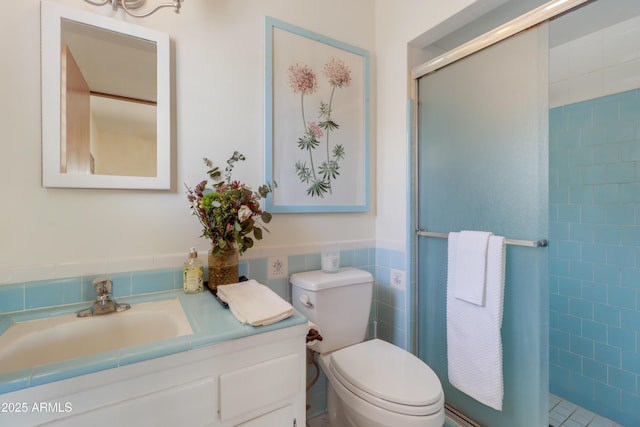 7526 E Edgemont Ave, Scottsdale, AZ 85251 - bathroom featuring tile walls, a stall shower, vanity, toilet, and a wainscoted wall