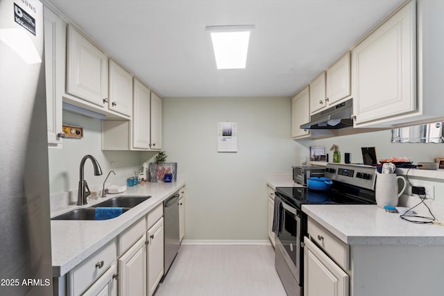 kitchen with light stone countertops, sink, white cabinets, and stainless steel appliances