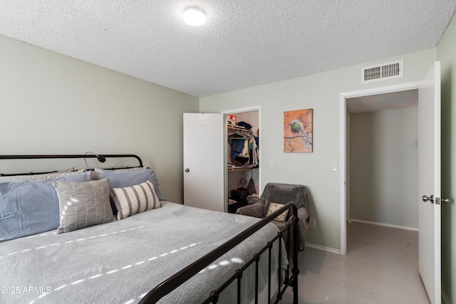 bedroom with a walk in closet, a closet, and a textured ceiling