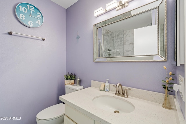 bathroom with vanity, toilet, and tiled shower