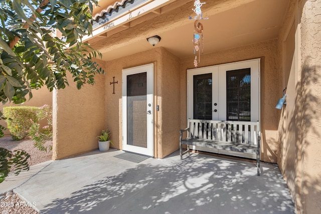 view of exterior entry with french doors and a patio area