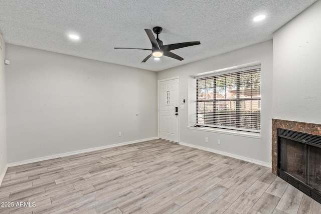 5704 E Aire Libre Ave Unit 1093, Scottsdale, AZ 85254 - unfurnished living room with ceiling fan, light wood-style floors, a textured ceiling, a tile fireplace, and recessed lighting