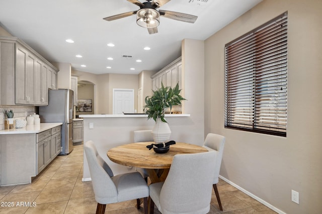 dining space featuring light tile patterned floors, baseboards, recessed lighting, arched walkways, and ceiling fan