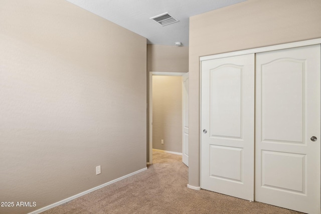 unfurnished bedroom with baseboards, visible vents, a closet, and light carpet