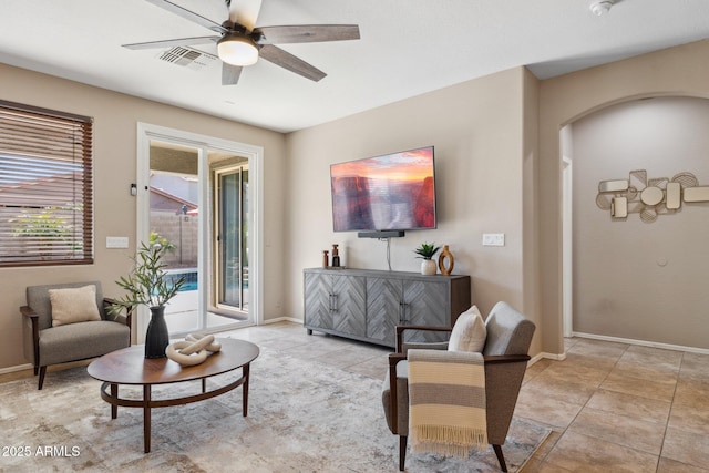 living area with visible vents, baseboards, ceiling fan, arched walkways, and light tile patterned flooring