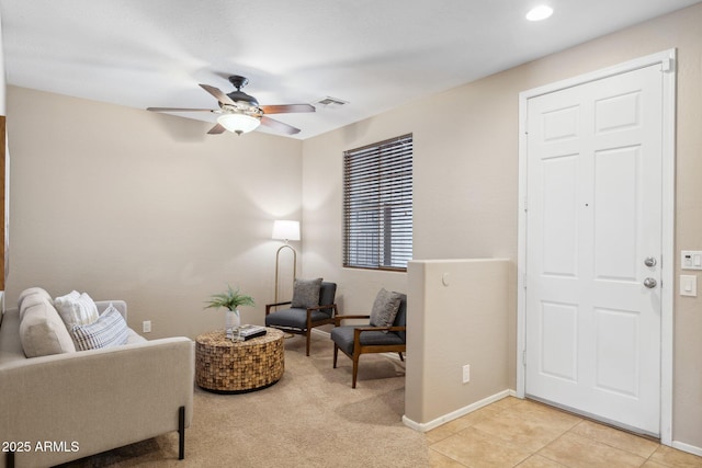 living area with light tile patterned flooring, visible vents, baseboards, and a ceiling fan