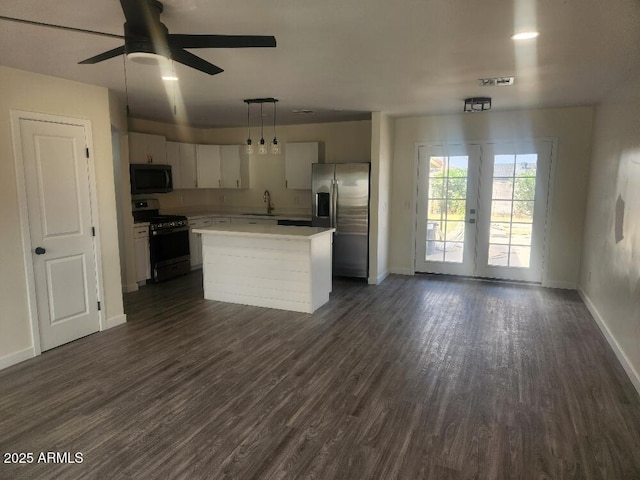 kitchen featuring gas stove, stainless steel refrigerator with ice dispenser, black microwave, baseboards, and white cabinetry