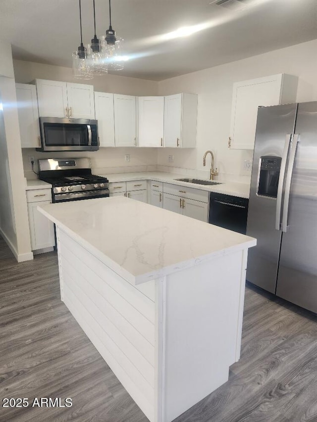kitchen with stainless steel appliances, a sink, a center island, white cabinetry, and dark wood-style floors