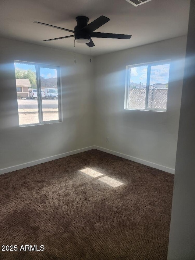carpeted spare room featuring healthy amount of natural light, ceiling fan, and baseboards