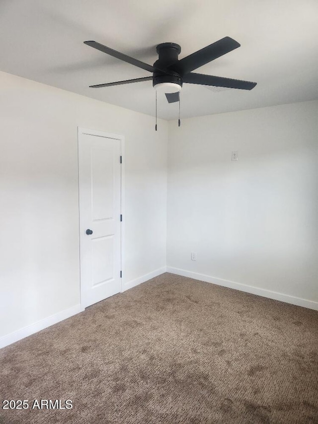 carpeted spare room featuring ceiling fan and baseboards