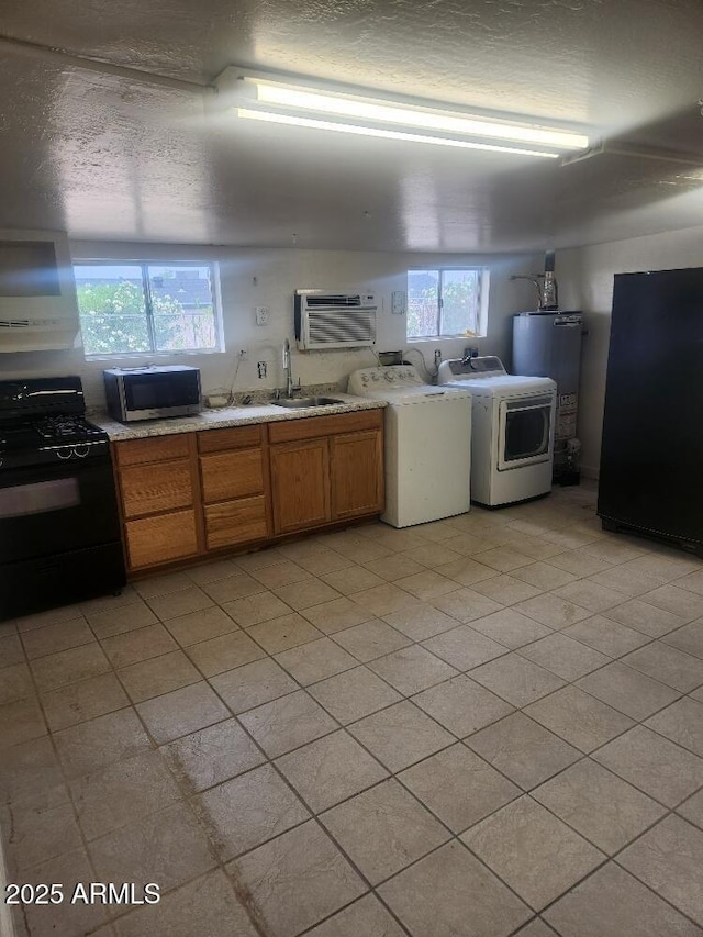 kitchen featuring black gas range, stainless steel microwave, separate washer and dryer, water heater, and a sink