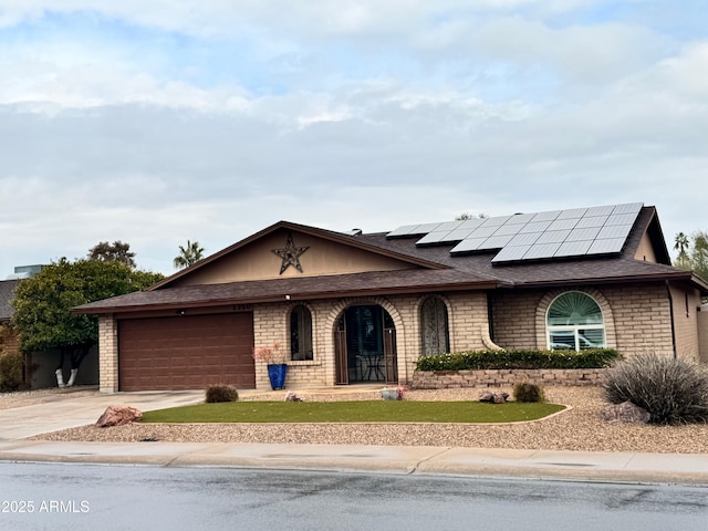 ranch-style home with a garage and solar panels