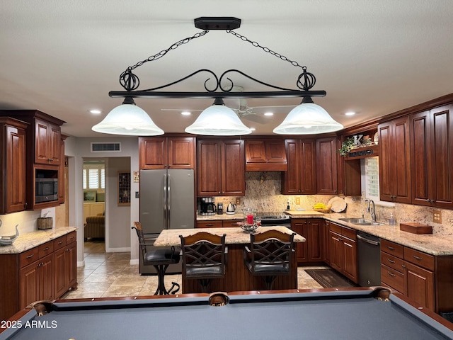 kitchen featuring a kitchen island, pendant lighting, billiards, sink, and stainless steel appliances