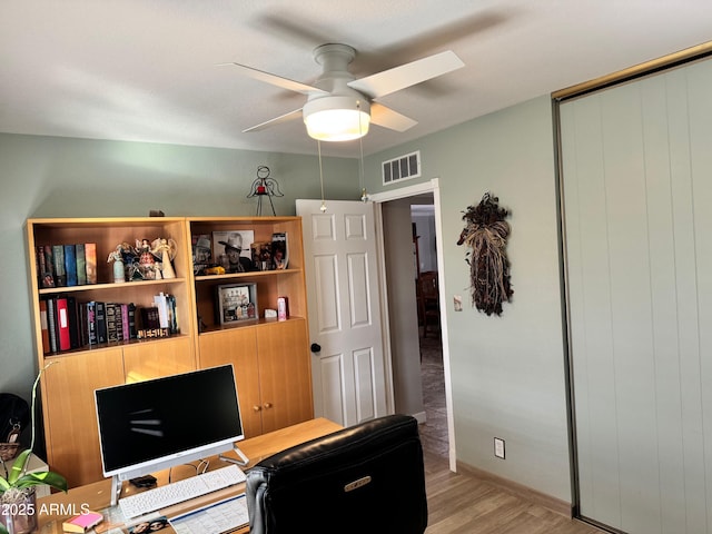 home office with light hardwood / wood-style floors and ceiling fan