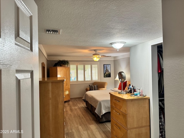 bedroom with light wood-type flooring, a textured ceiling, and ceiling fan