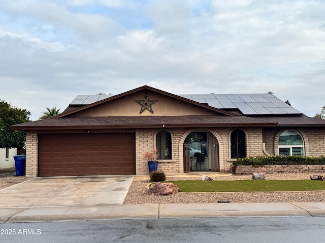 ranch-style home featuring a garage and solar panels