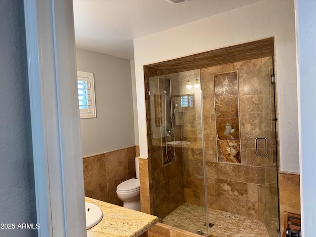 bathroom with vanity, tile walls, walk in shower, and toilet