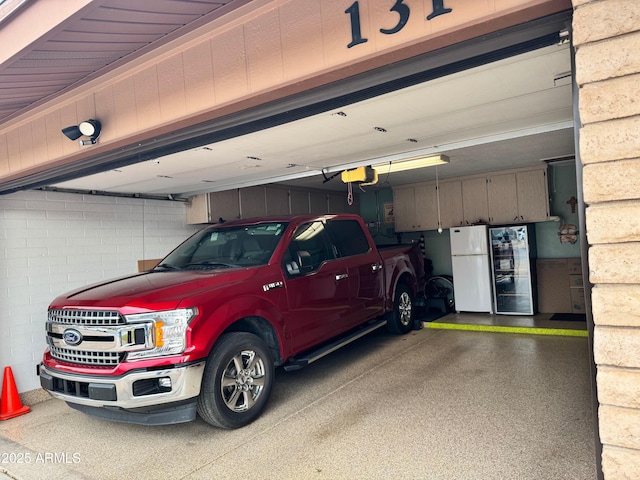 garage featuring white refrigerator and a garage door opener