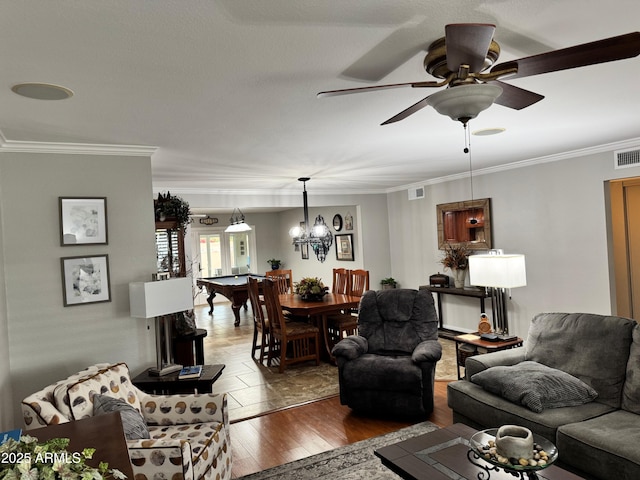 living room with crown molding, ceiling fan with notable chandelier, and hardwood / wood-style floors