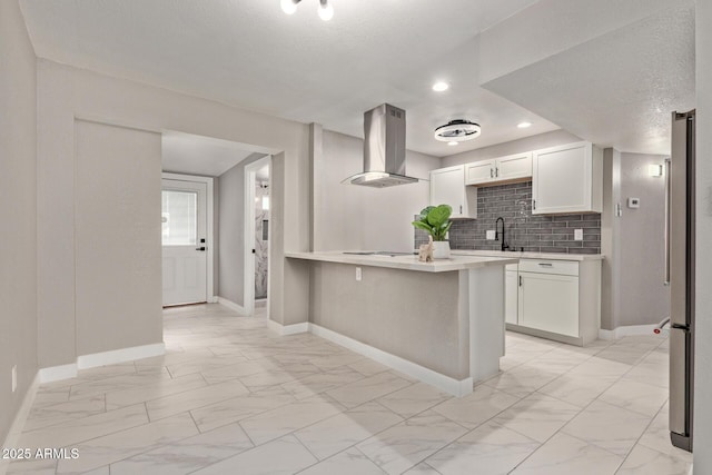 kitchen featuring stainless steel refrigerator, tasteful backsplash, white cabinets, island exhaust hood, and kitchen peninsula