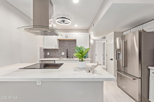 kitchen featuring sink, white cabinetry, island range hood, light stone countertops, and high end refrigerator