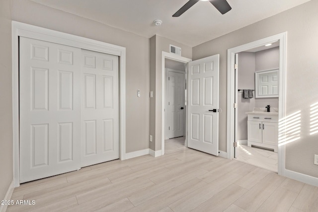 unfurnished bedroom featuring ensuite bath, light hardwood / wood-style flooring, a closet, and ceiling fan