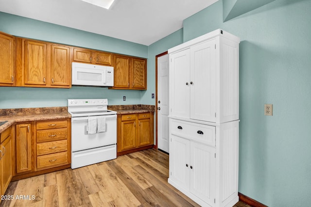 kitchen with light wood-type flooring, white appliances, and brown cabinets