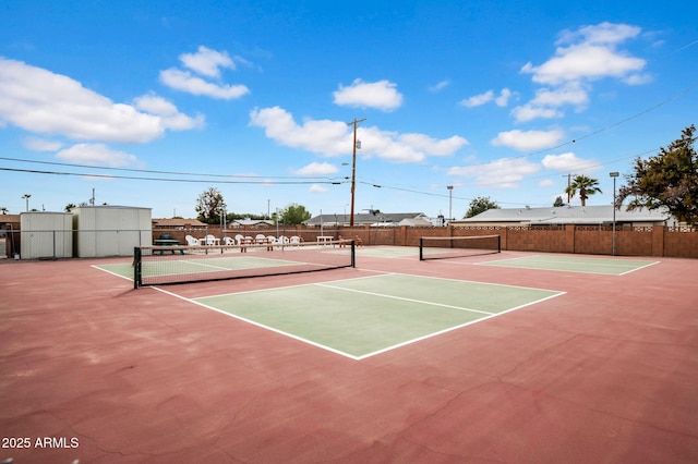 view of tennis court with community basketball court and fence