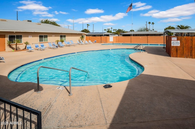 pool with a patio area and fence