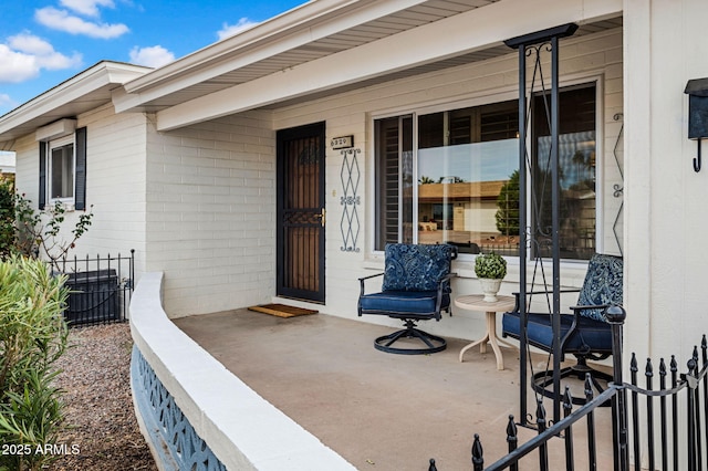 entrance to property with covered porch, central AC unit, and concrete block siding