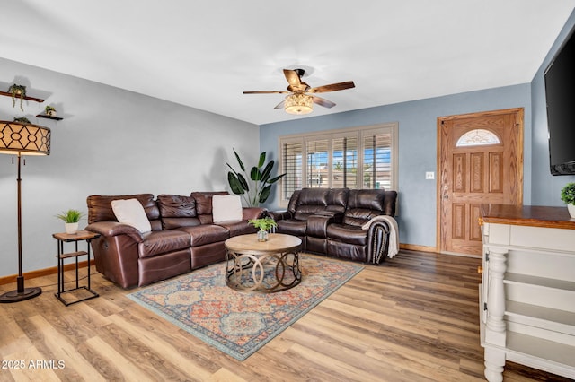 living room featuring baseboards, a ceiling fan, and light wood-style floors