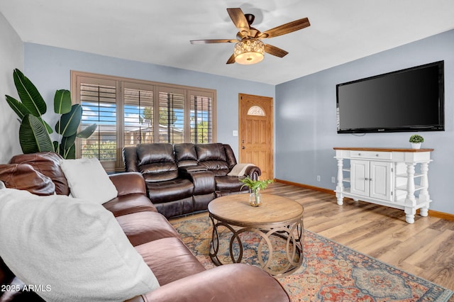 living area with a ceiling fan, light wood-style flooring, and baseboards