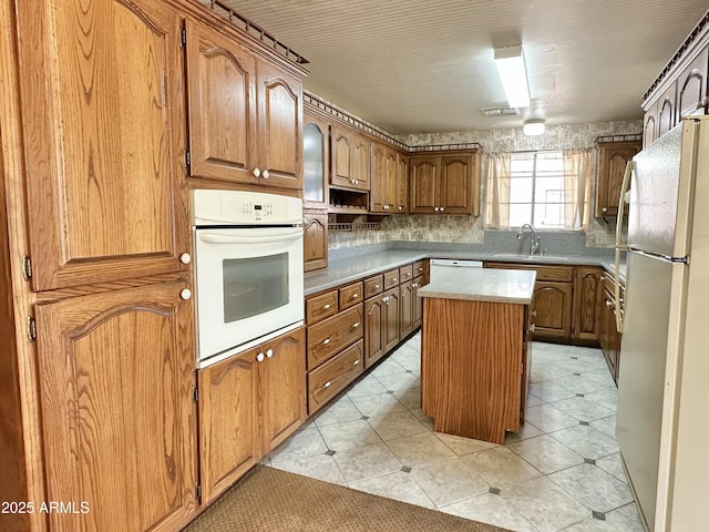 kitchen featuring white oven, refrigerator, sink, tasteful backsplash, and a kitchen island