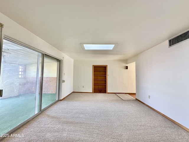 carpeted empty room featuring a skylight, built in features, and a healthy amount of sunlight