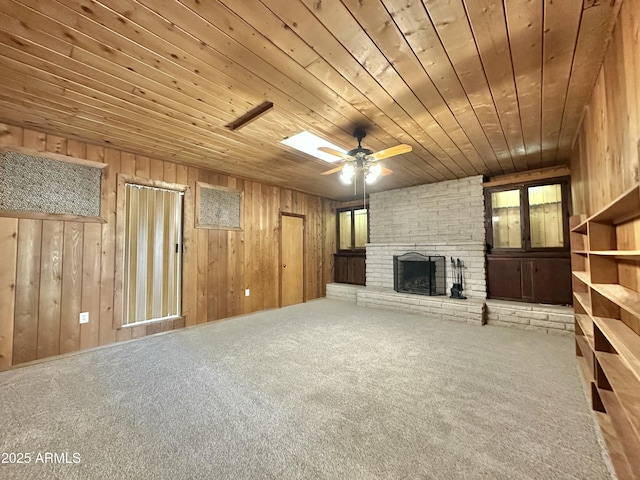 unfurnished living room with ceiling fan, carpet floors, wooden ceiling, and a brick fireplace