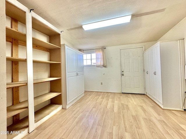 basement with light hardwood / wood-style floors and a textured ceiling