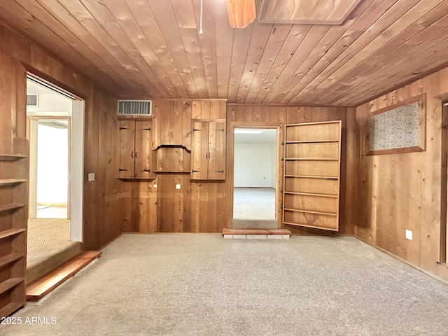 interior space featuring carpet, wood walls, and wooden ceiling