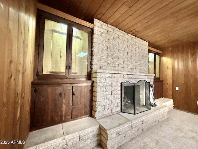 unfurnished living room with a fireplace, light colored carpet, wood ceiling, and wood walls