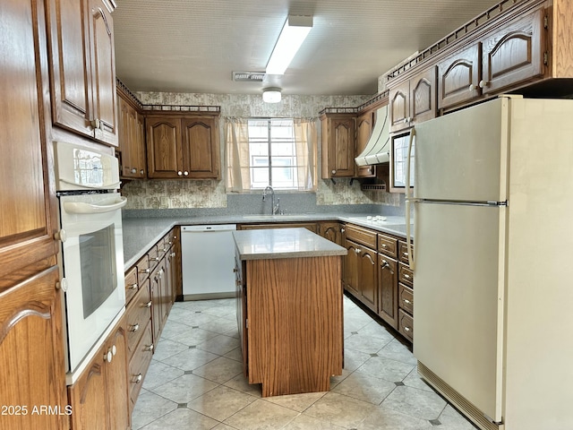 kitchen featuring a kitchen island, white appliances, sink, and range hood