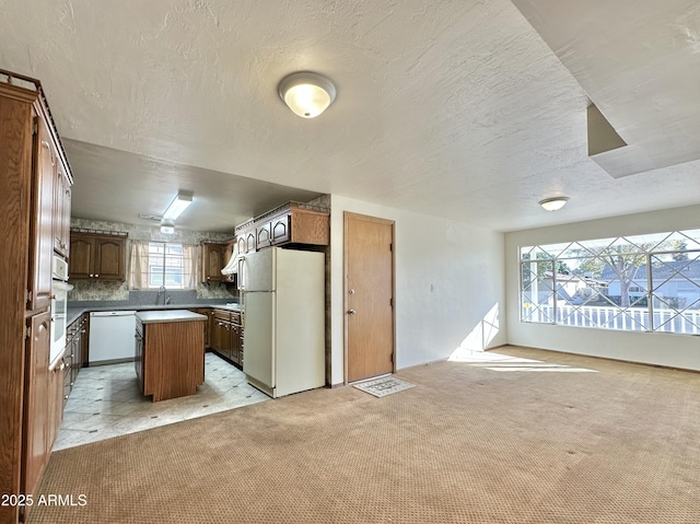 kitchen featuring sink, a kitchen island, light colored carpet, and white appliances