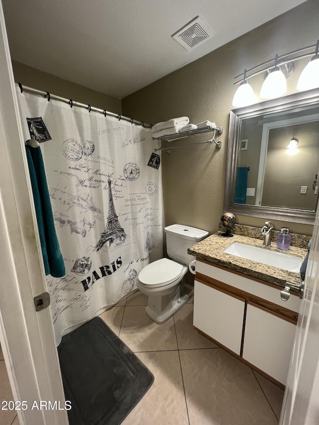 bathroom with tile patterned floors, visible vents, toilet, vanity, and a textured wall