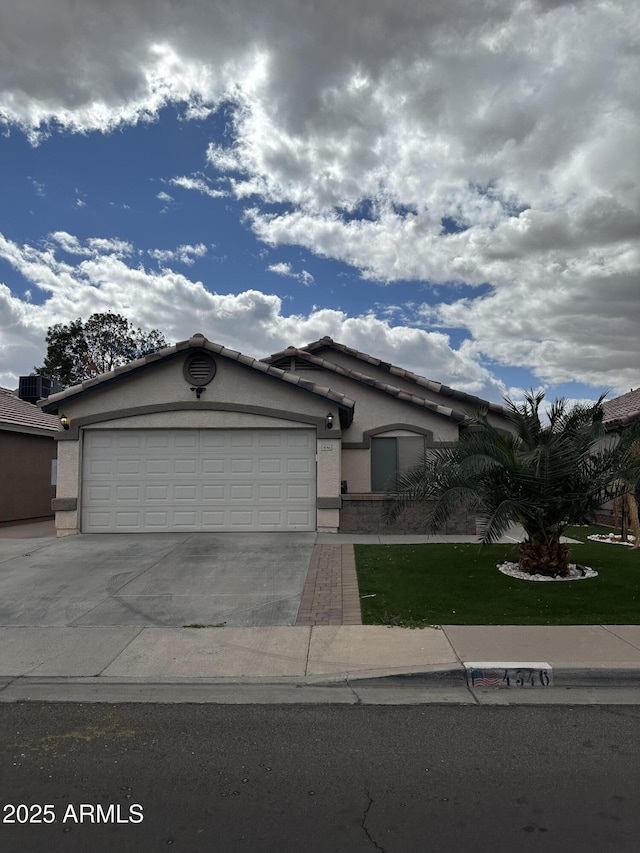 view of front of house with stucco siding, an attached garage, driveway, and a tiled roof