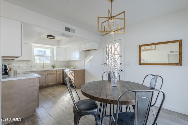 dining area featuring an inviting chandelier, light hardwood / wood-style flooring, and sink