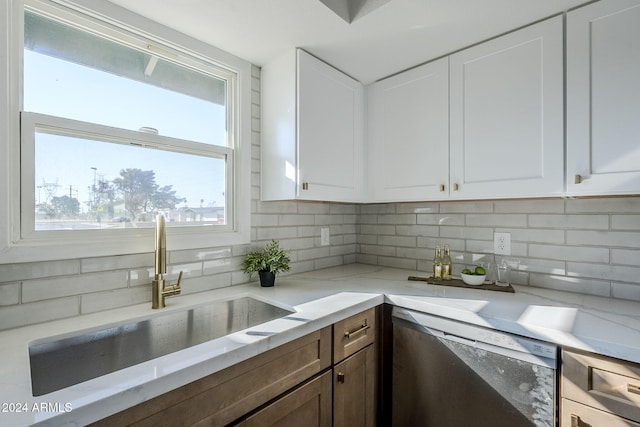 kitchen with dishwasher, backsplash, white cabinets, sink, and light stone counters