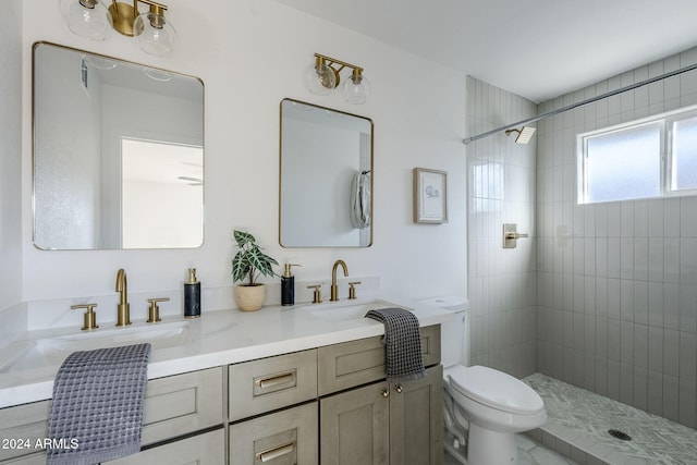 bathroom featuring a tile shower, vanity, and toilet