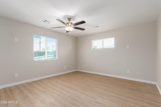 empty room featuring ceiling fan, light hardwood / wood-style floors, and a healthy amount of sunlight