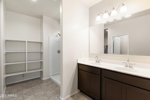 bathroom with double vanity, a sink, walk in shower, and tile patterned floors