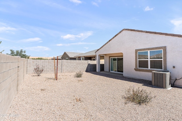rear view of house featuring stucco siding, central AC unit, and a fenced backyard