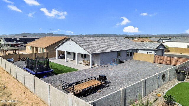 27550 N Silverleaf Rd, San Tan Valley, AZ 85143 - back of house featuring a trampoline, a patio area, stucco siding, and a fenced backyard
