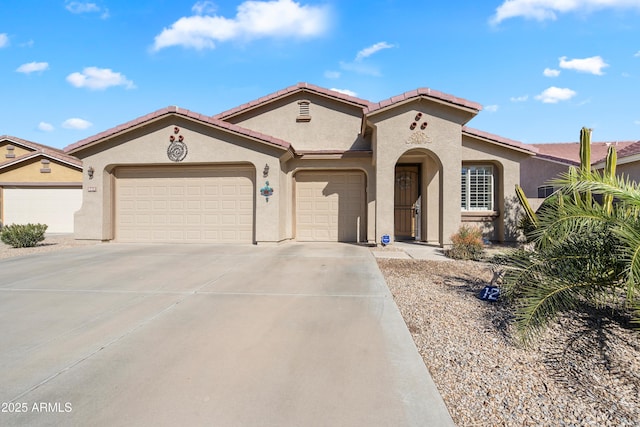 mediterranean / spanish house featuring a garage, driveway, a tile roof, and stucco siding